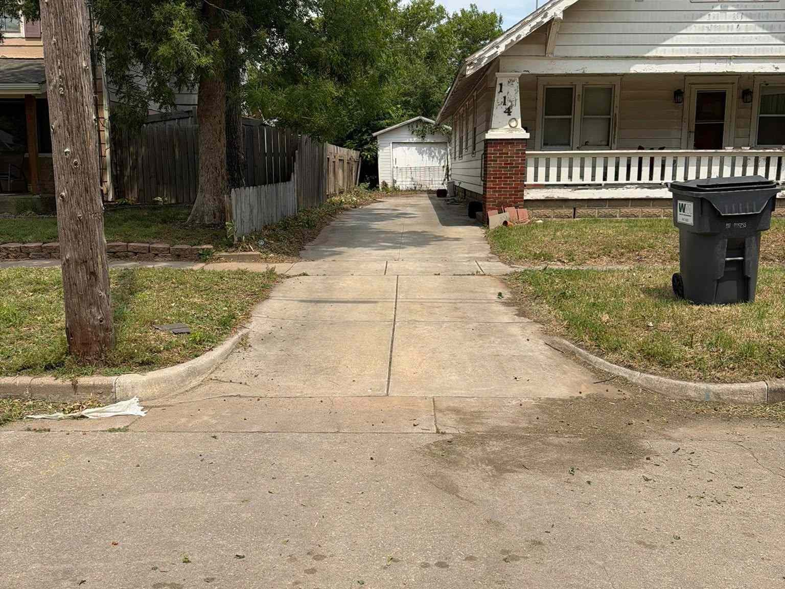 A residential sidewalk with a grassy verge and a tree